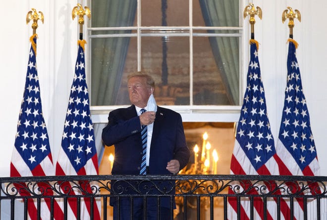 U.S. President Donald Trump removes his mask upon return to the White House from Walter Reed National Military Medical Center on October 5, 2020 in Washington, DC. Trump spent three days hospitalized for coronavirus.