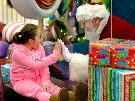 Madalynn Brooks, 7, of Canadohta Lake, visits with Santa Claus at the Millcreek Mall, Saturday, Dec. 12, 2020, in Millcreek Township, Pa. Santa, portrayed by Lenny Chatt, 73, of Lawrence Park, was seated behind a sheet of plexiglass due to COVID-19 safety measures.