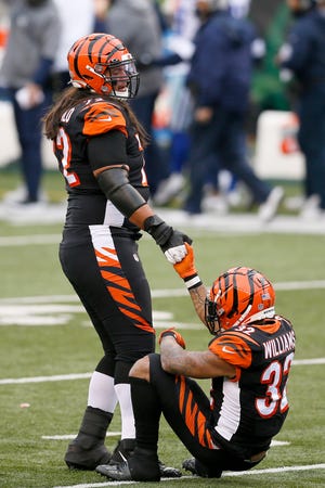 Cincinnati Bengals running back Trayveon Williams (32) is pulled to his feet by offensive guard Xavier Su'a-Filo (72) after fumbling a handoff, resulting in a touchdown, in the first quarter of the NFL Week 14 game between the Cincinnati Bengals and the Dallas Cowboys at Paul Brown Stadium in downtown Cincinnati on   Sunday, Dec. 13, 2020. The Cowboys led 17-7 at half time. 