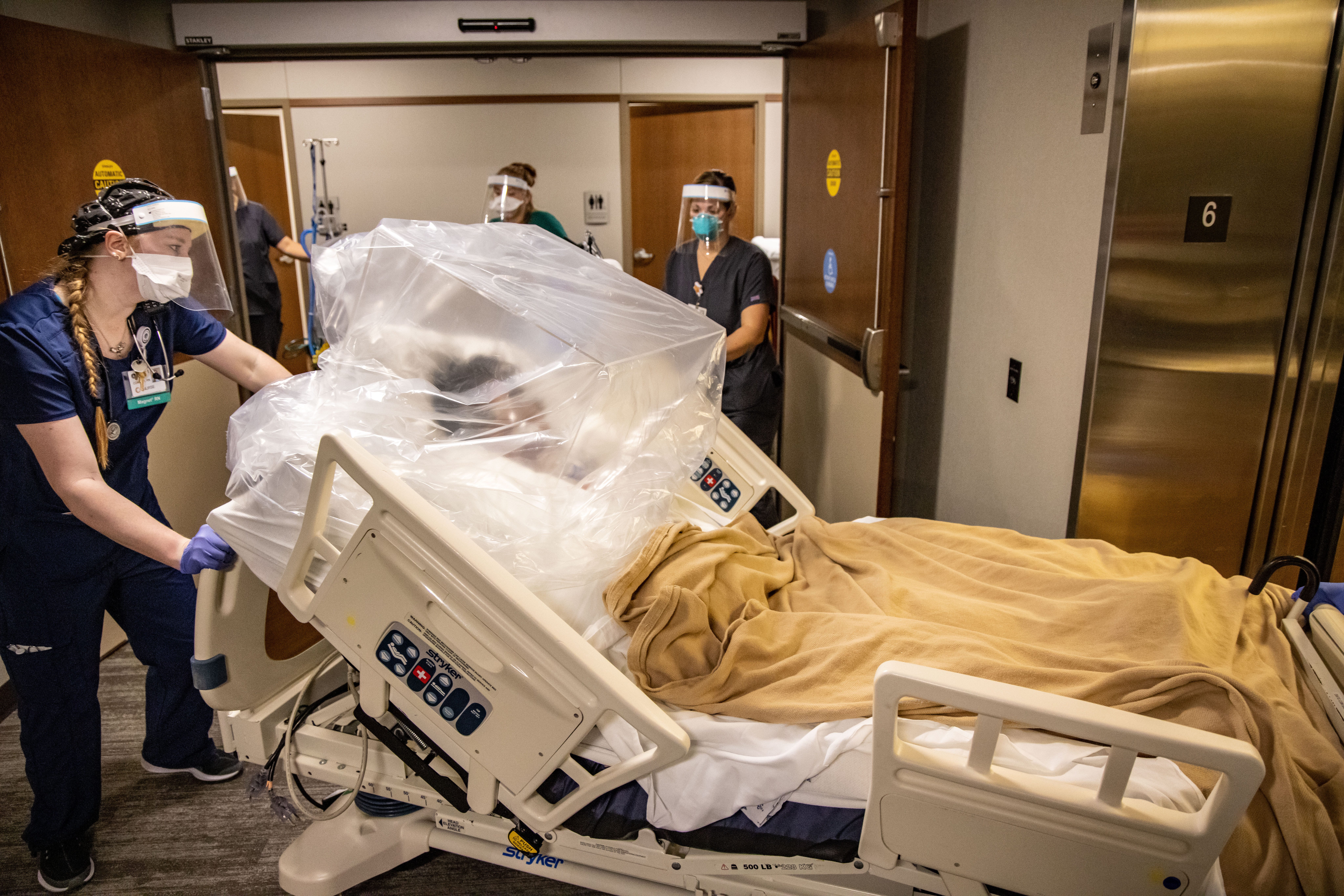 9:25 a.m., DES MOINES - Nurse Connor Ramirez calls environmental services to report the elevator number as she moves a COVID-19 patient to the ICCU at Mary Greeley Medical Center. Environmental services will disinfect the elevator as soon as the patient is removed. The plexiglass box and bag are placed over the patient while in transit to help control the spread of COVID-19.