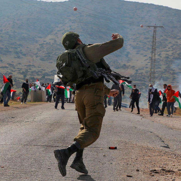 An Israeli soldier throws teargas against Palestinian protesters during a protest against Jewish settlements on November 24, 2020, in the Jordan Valley in the Israeli-occupied West Bank. 