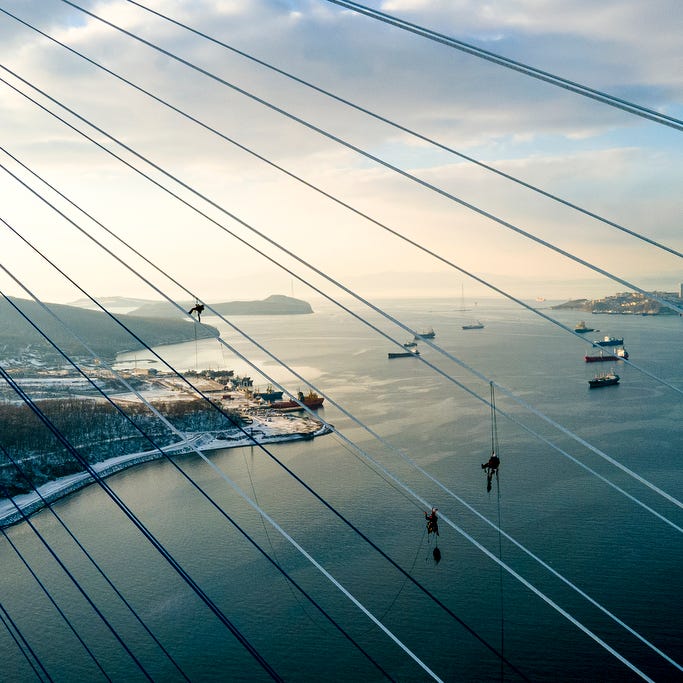 Industrial climbers remove ice from the cables of the Russky Bridge across the Eastern Bosphorus Strait in Vladivostok, Russia, Monday, November 30, 2020.