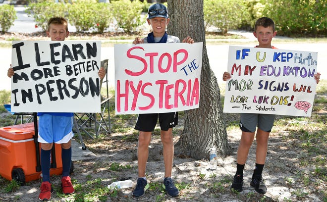 Students hold signs opposing COVID-19-related school closures during a protest outside a Sarasota County School Board meeting in July.