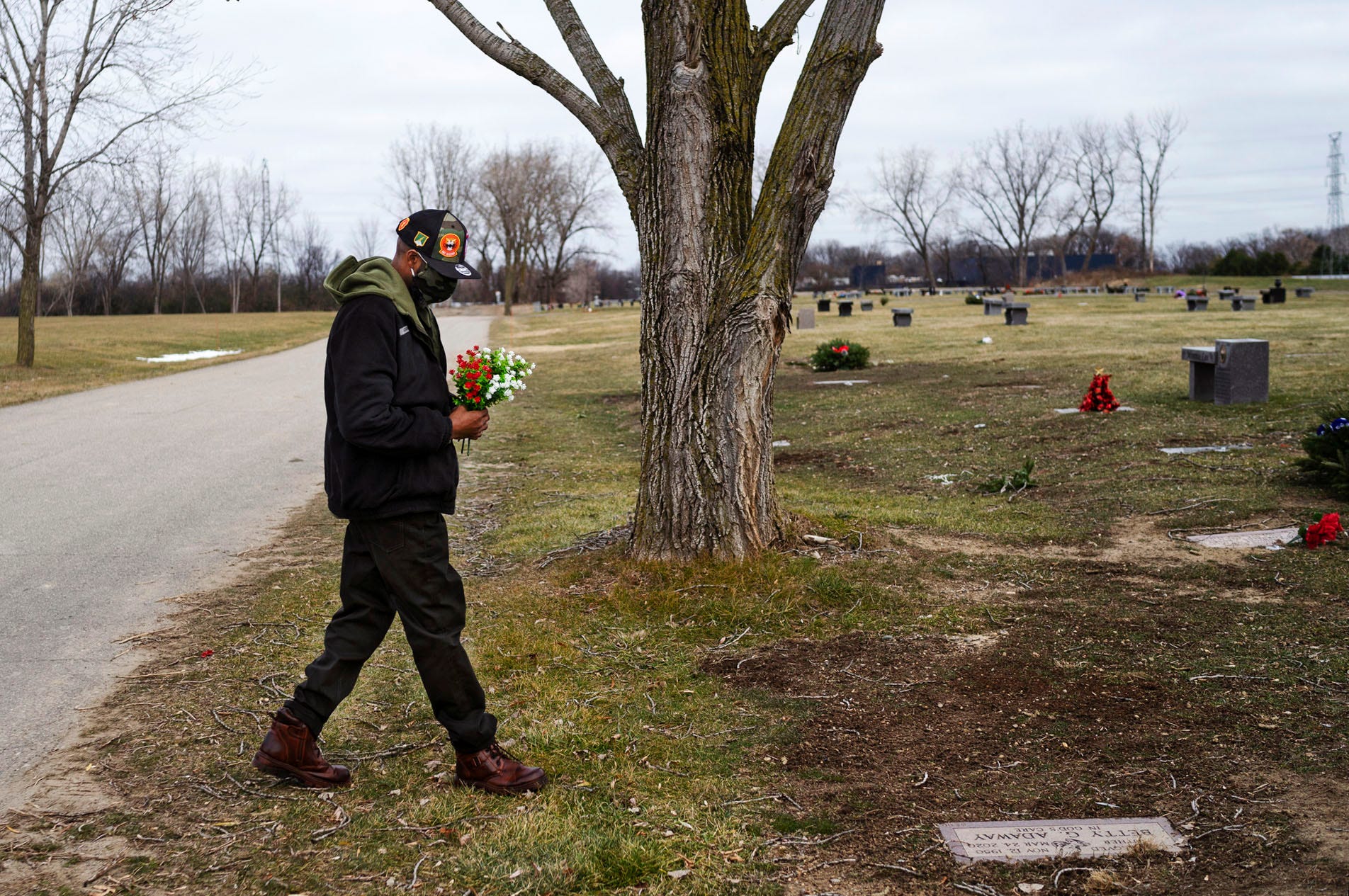 David Adaway places flowers on his mother's grave at the Detroit Memorial Park on Sunday, Dec. 6, 2020, in Redford Township.