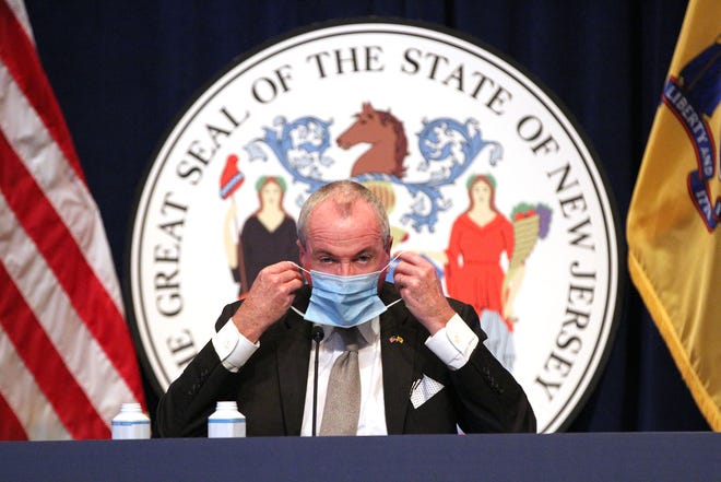 New Jersey Governor Phil Murphy puts his mask on at the end of his Monday, December 14, 2020, briefing on the State's COVID-19 response at the Trenton War Memorial