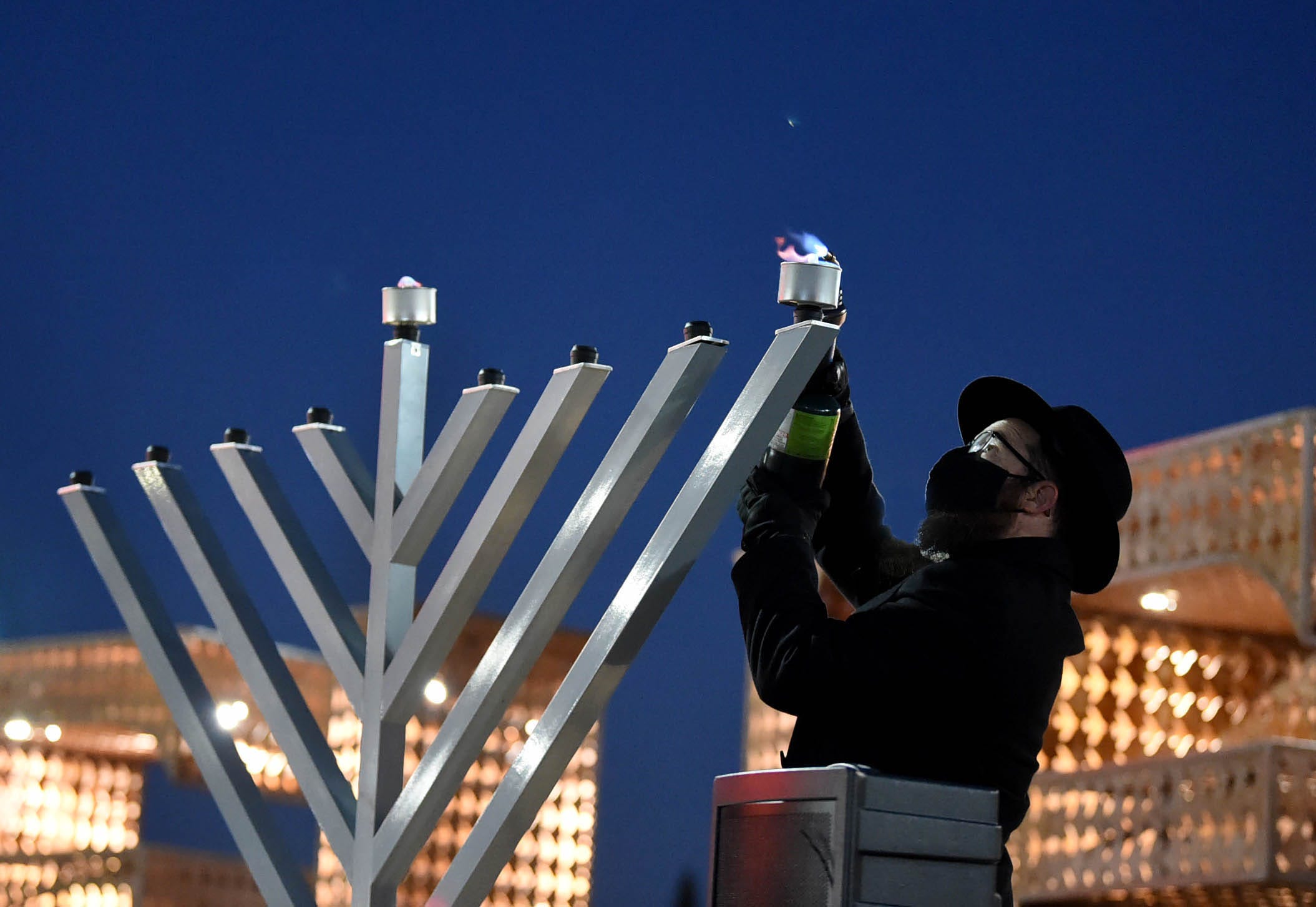 Rabbi Mendel Cunin lights the first candle of the menorah on the first day of Hanukkah during a non-public menorah lighting ceremony on the Reno City Plaza on Thursday Dec. 10, 2020.