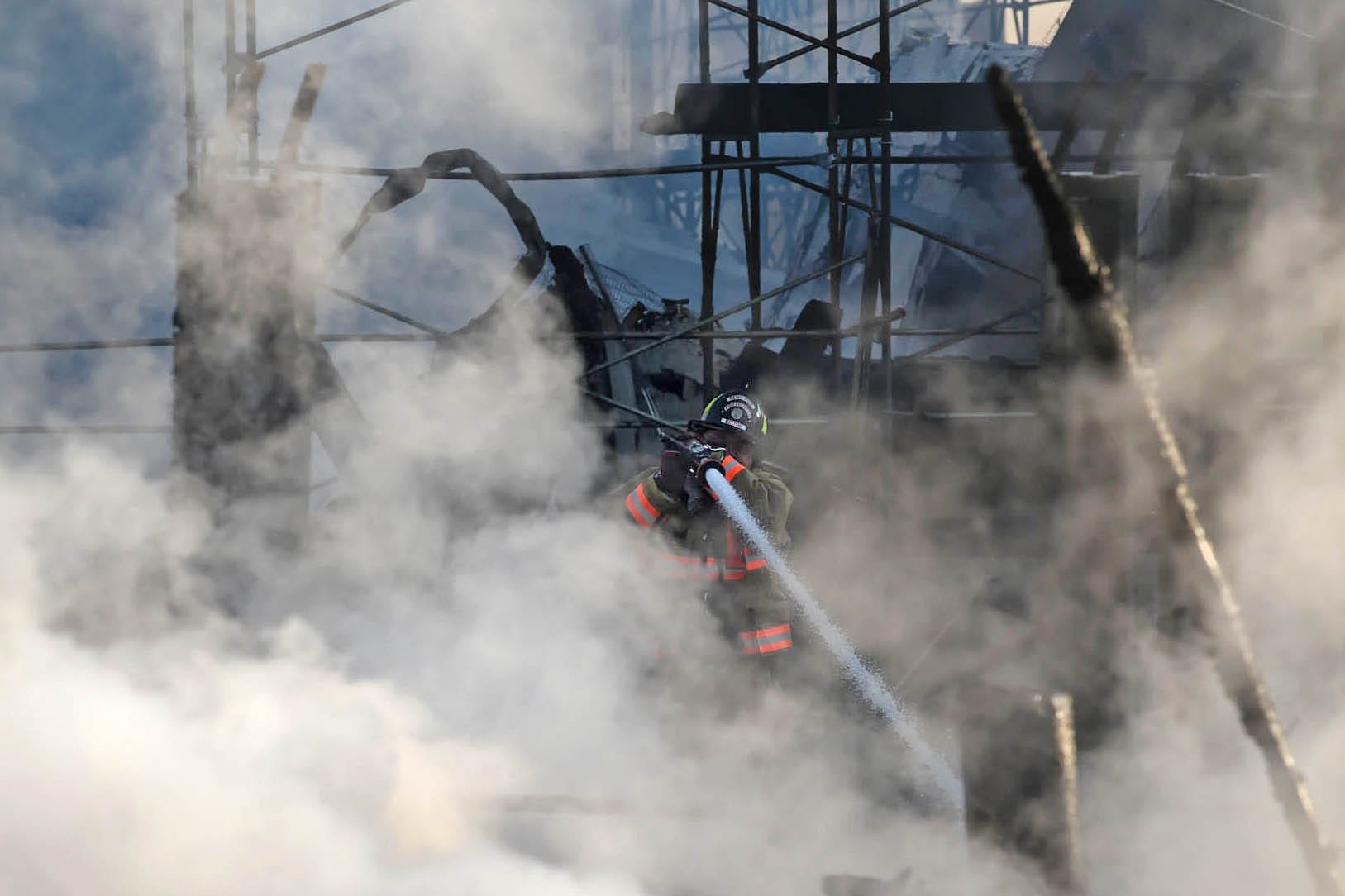 A Reno Firefighter hits a hot spot as they battle fire at a townhome complex under construction in south Reno early in the morning on Thursday July 23, 2020.