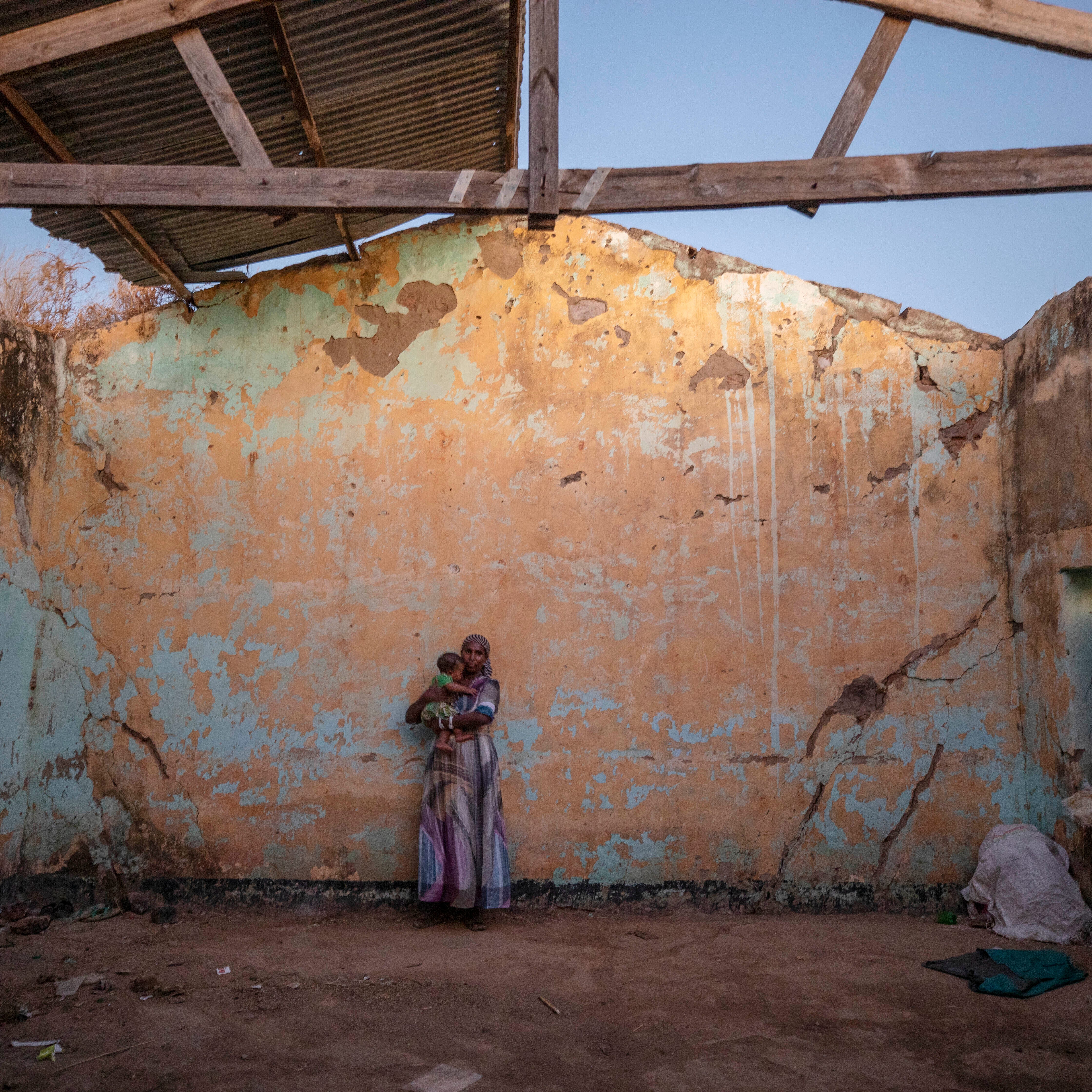 A woman who fled the conflict in Ethiopia's Tigray region holds her child inside of her temporary shelter at Umm Rakouba refugee camp in Qadarif, eastern Sudan, Monday, December 7, 2020.