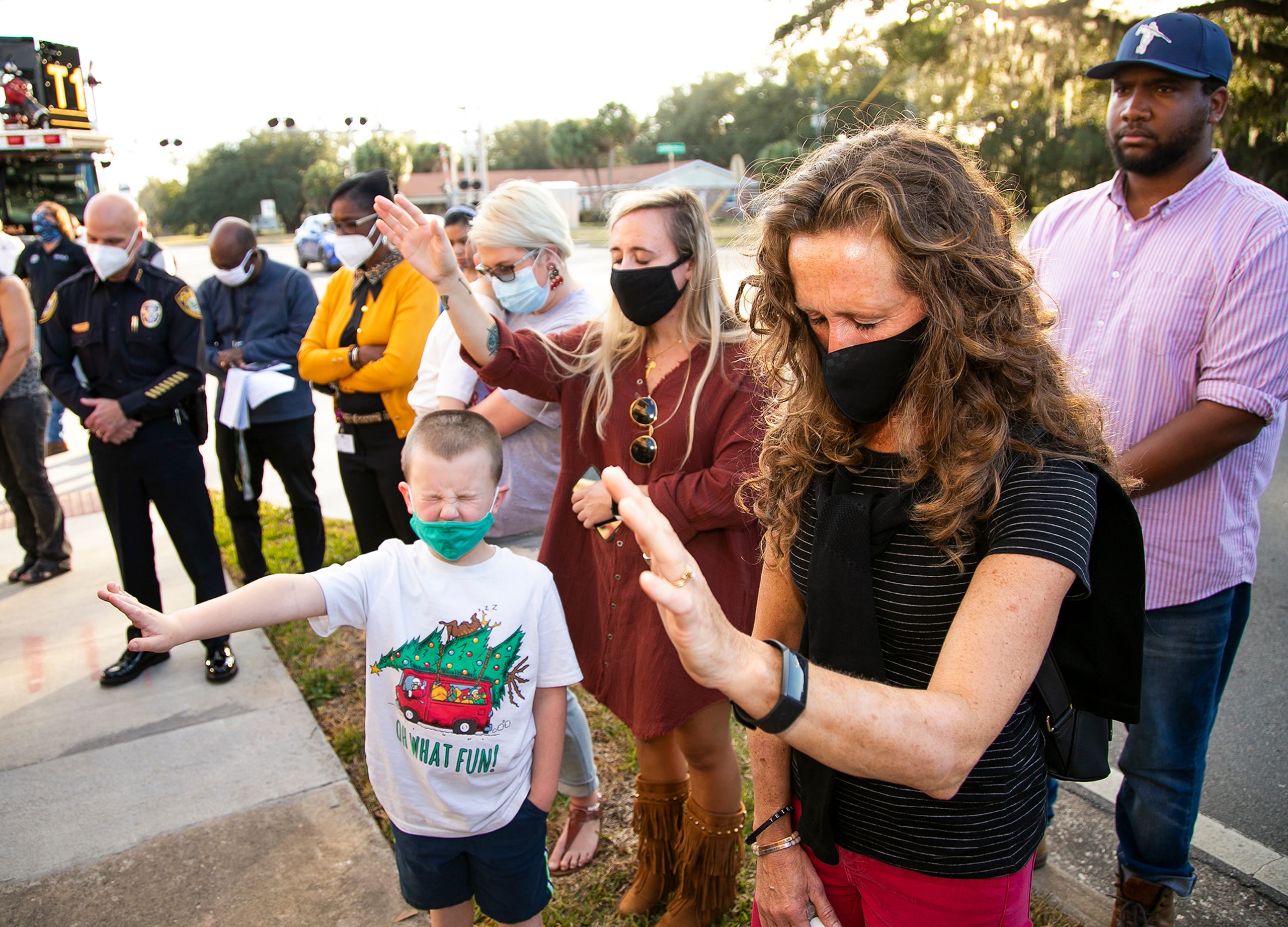 Linda Cummins, right, holds her hand up during prayer with others while blessing the Safe Haven Baby Box Drop Off  after it was unveiled at Ocala Fire Station #1 Tuesday afternoon, December 15, 2020 at the new MLK First Responders Campus. The founders of the device, Monica Kelsey and her husband Joe Kelsey were on hand for the unveiling. Monica was a baby of rape and has a passion for the cause. The device was designed for the safe, secure and anonymous surrender of a newborn by a mother in crisis. The SHBB is equipped with cooling and heating features, locking mechanisms and alarm systems that trigger an immediate response through 9-1-1. [Doug Engle/Ocala Star Banner]2020