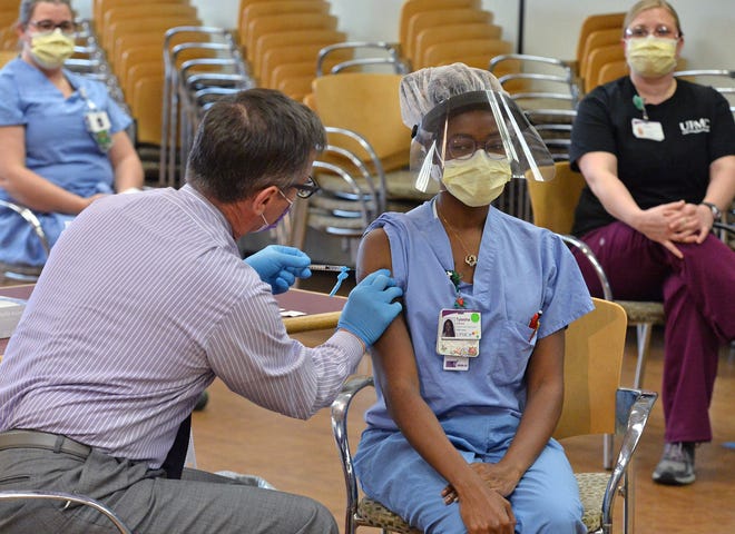 At UPMC Hamot on December 17, James Donnelly, RN, left, Tylesha Williams, 26, right, gives a patient care technician at UPMC Hamot the first COVID-19 vaccination in Erie.