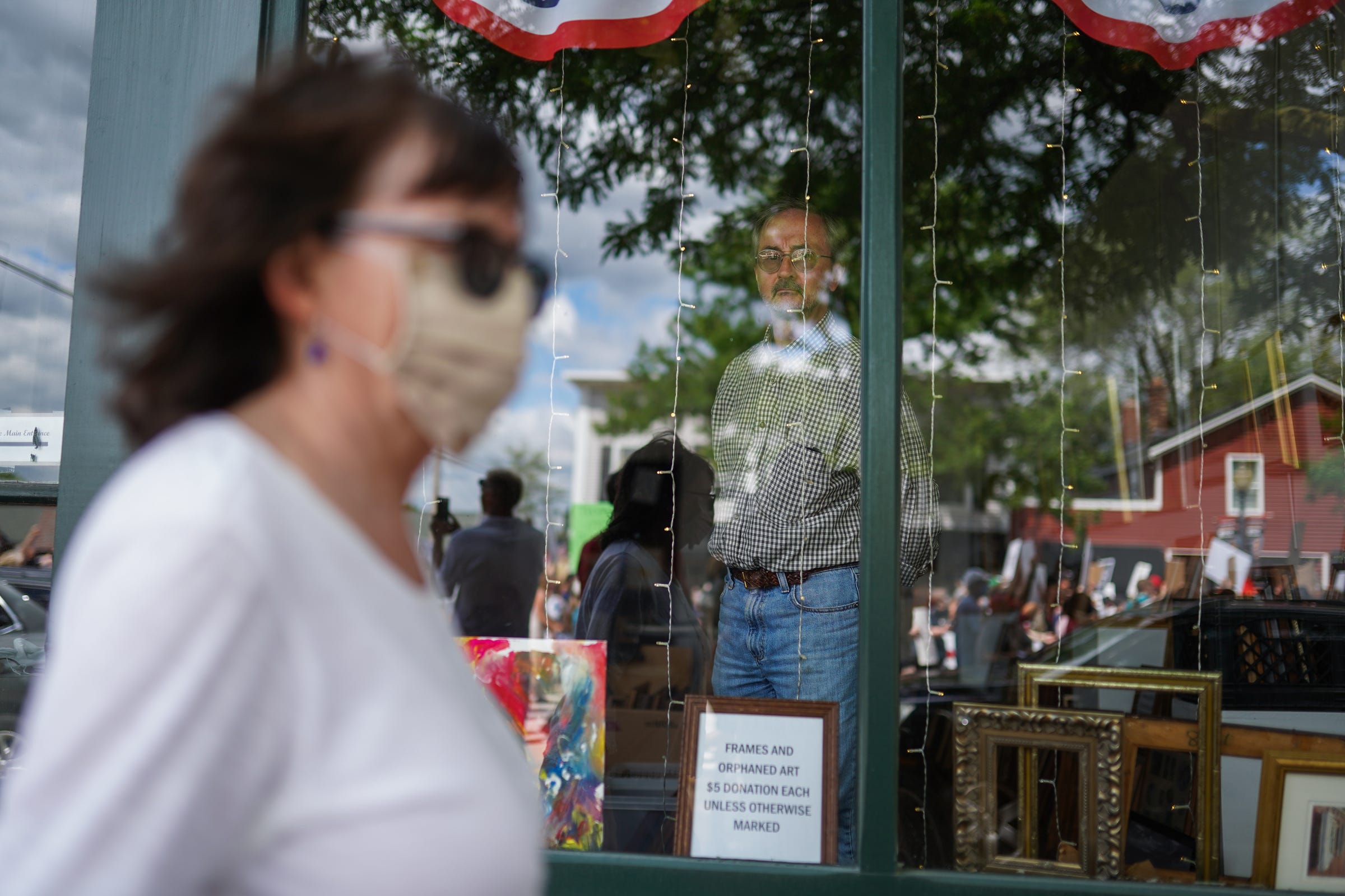 People watch a crowd of protesters march along North Main Street in downtown Romeo during the Romeo March for Racial Justice on Friday, June 12, 2020.