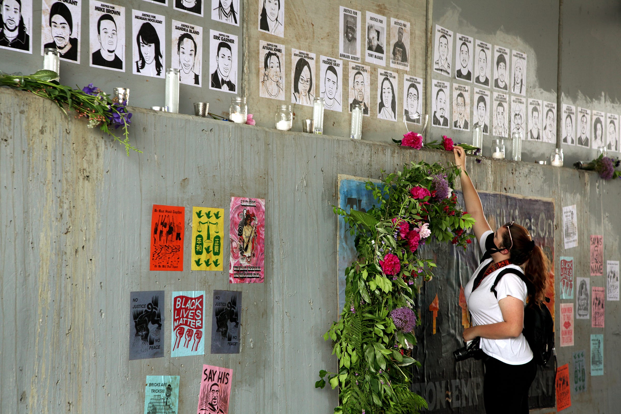 Makaylah Owens of Dearborn places a flower on a memorial commemorating Black lives lost to violence while protesters wait for the march to start at the entrance to the Dequindre Cut near Eastern Market on June 6, 2020, in Detroit The nearly 500-person march walked the Dequindre Cut to the Riverwalk.