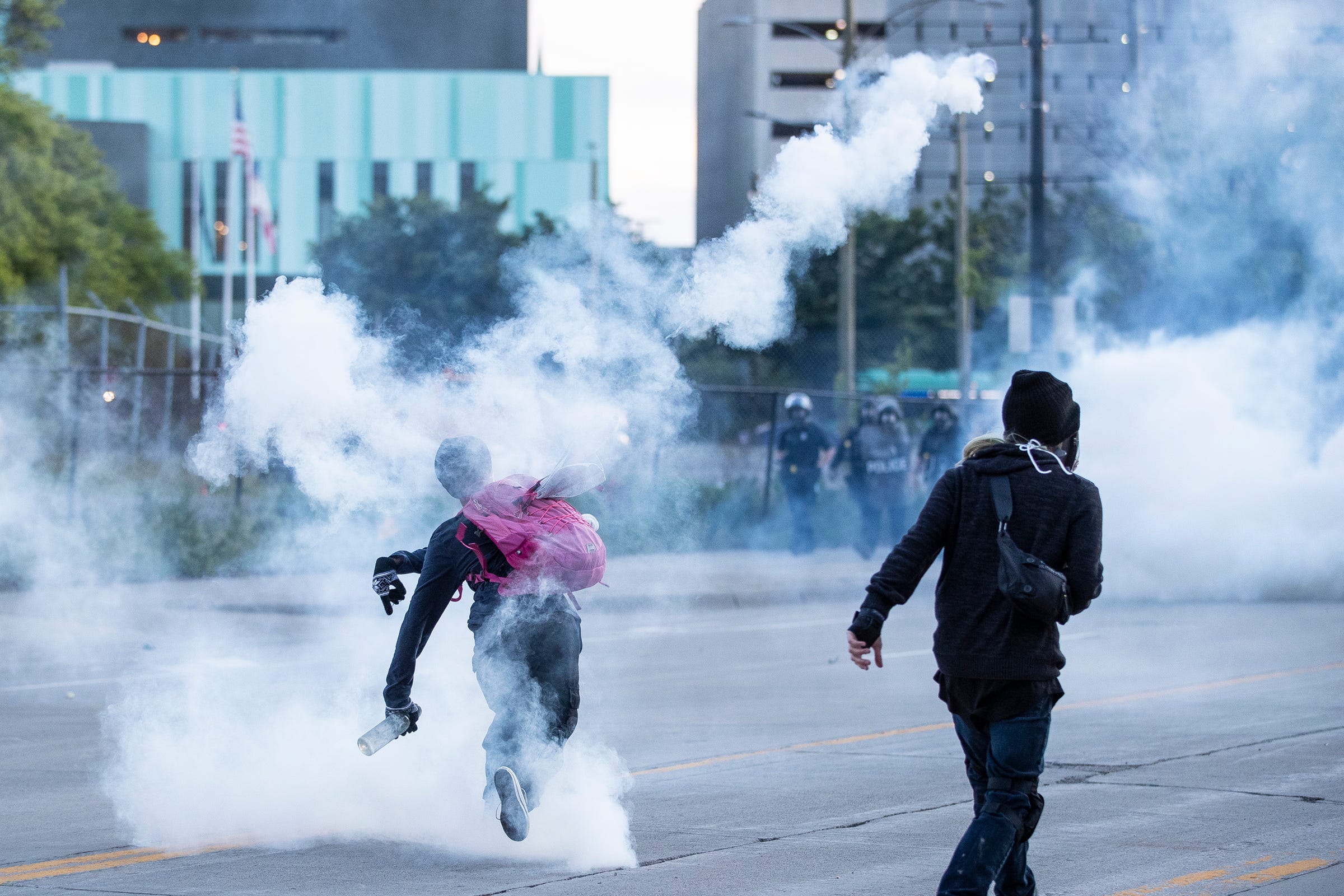 Protesters try to throw the tear gas can back at the Detroit police on Michigan Avenue in Detroit, Sunday, May 31, 2020.