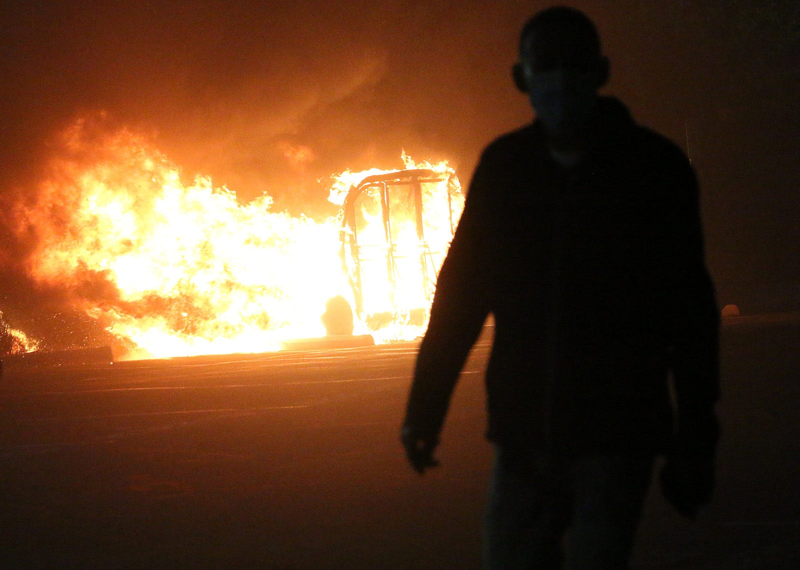 A protester walks in front of a burning vehicle during the Black Lives Matter rally and civil unrest in Reno on May 30, 2020.