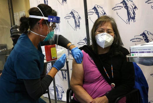 Community Health Supervisor Cordelia Abel-Johnson, right, receives one of the first COVID-19 Phizer vaccination in the state of Nevada at the Reno-Sparks Tribal Health Center in Reno on Dec. 16, 2020. The vaccination is seen being administered by Registered Nurse Veronica Crawford.
