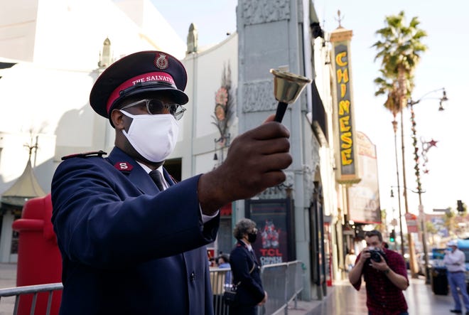 Maj. Osei Stewart of The Salvation Army rings a bell to alert passersby and drivers of the charitable organization's drive-through donations event at the TCL Chinese Theatre, Thursday, Dec. 10, 2020, in Los Angeles.