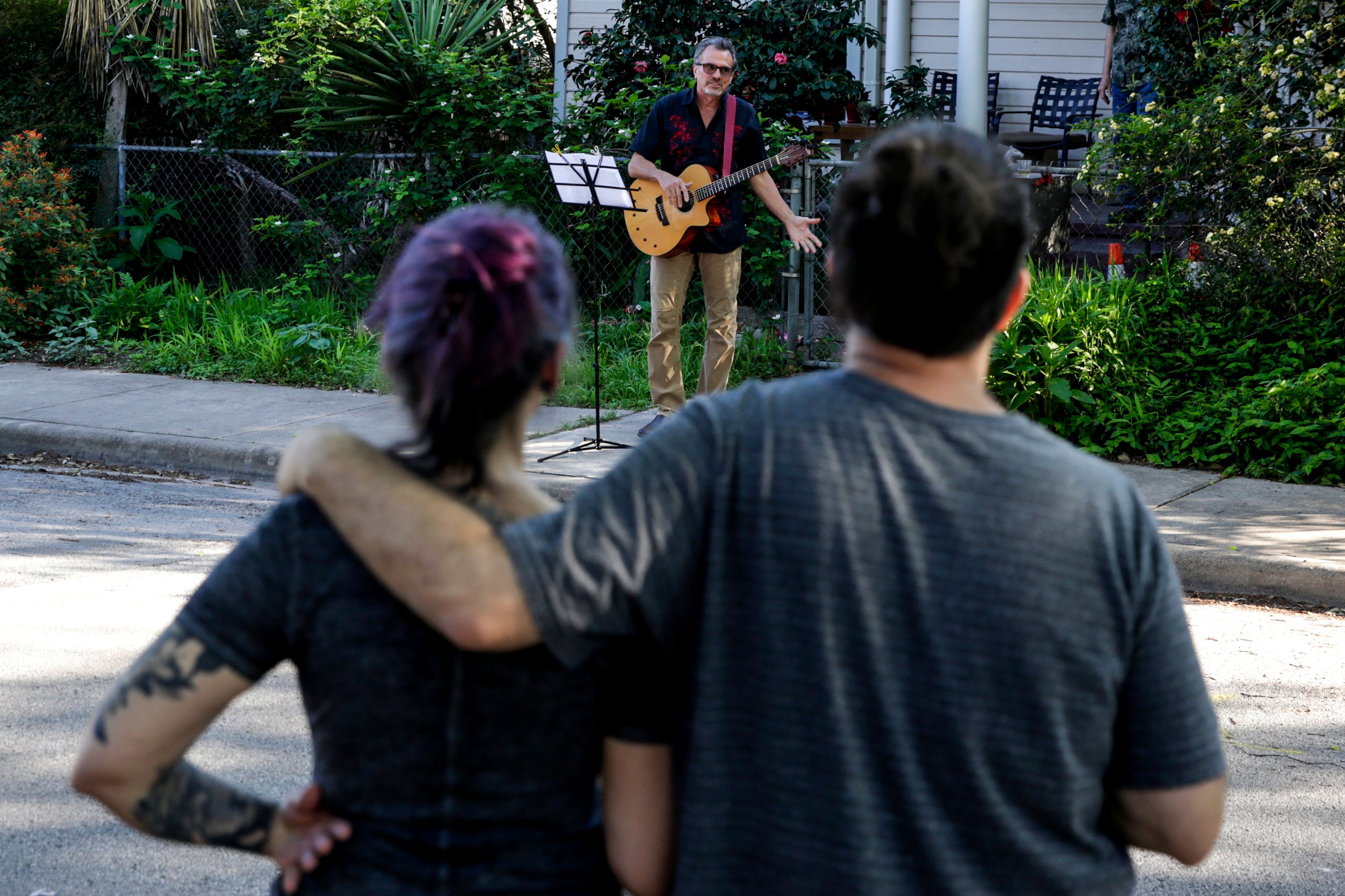 Guitarist David Kendall sings "Don't Stand So Close To Me" by The Police with his neighbors in a neighborhood off East Cesar Chavez in Austin on Tuesday, March 24, 2020. Kendall along with a few other neighbors started the neighborhood singalong in order to lift spirits during the city's response to the known coronavirus.