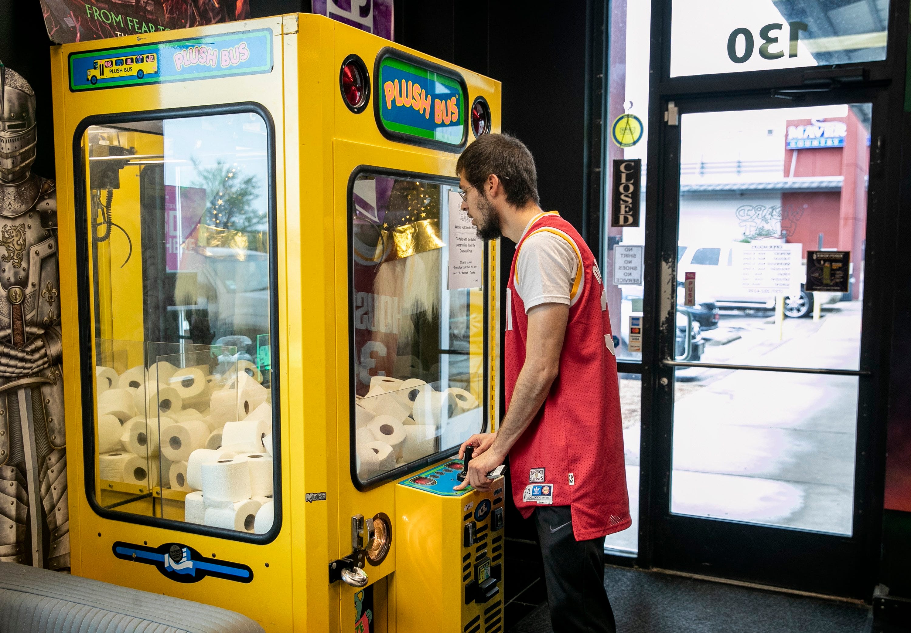 Jose Medellin tries his luck winning a roll of toilet paper from a claw machine arcade game at Wizard Hat Smoke Shop in Pflugerville, Texas, on Sunday March 15, 2020.  The arcade game was filled with rolls of toilet paper as a lighthearted reaction to the toilet paper shortage caused by the coronavirus outbreak.  Medellin said he just returned from a weeklong trip to California, and he's getting low on toilet paper.  "I couldn't find any toilet paper at H-E-B, and Sam?s Club is out," he said. "For 50 cents, why not?"