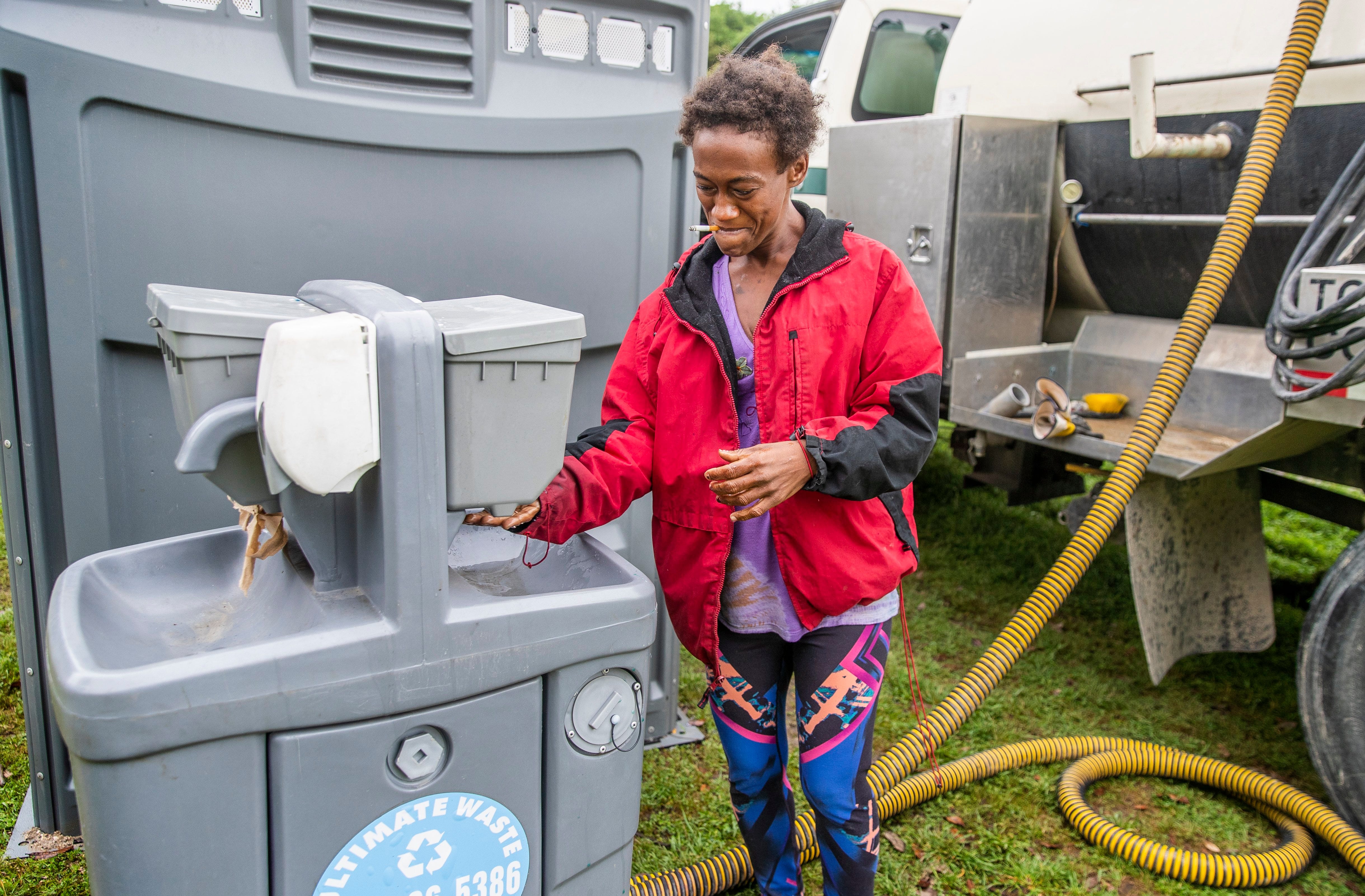 Levon Shyrell washes her hands at a portable station on at Riverside Dr, Austin  Tuesday, March 31, 2020. Texas Disposal Systems team up with the City of Austin to provide hand washing and portable restroom station for the Homeless around Austin. officials have leased a hotel to isolate people who are homeless who test positive for the coronavirus. City staff have also outlined a broad plan to educate the homeless community about the virus, while providing locations to shower, use bathrooms and sanitize to the best of their ability Tuesday, March 31, 2020