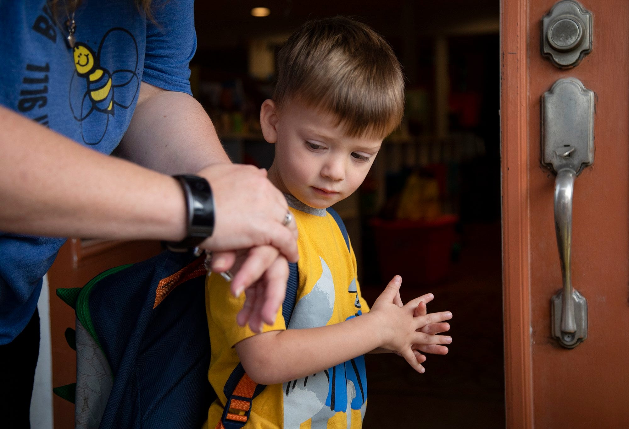 Sarah Smith, the owner of Busy Bee Academy,  reminds Jefferson Orozco, 3, how to properly use hand sanitizer before he enters the daycare on April 9, 2020, in Bastrop, Texas. Children with a temperature of 100.4 won't be accepted at drop off. The business had about 140 children enrolled in their daycare program before the coronavirus. It now has about 40 to 50 children each day for essential workers only. Smith checks each child's temperature and disinfects the children's shoes and has them use hand sanitizer before entering the building. Smith said the state notified her by e mail with regulation changes on March 15.