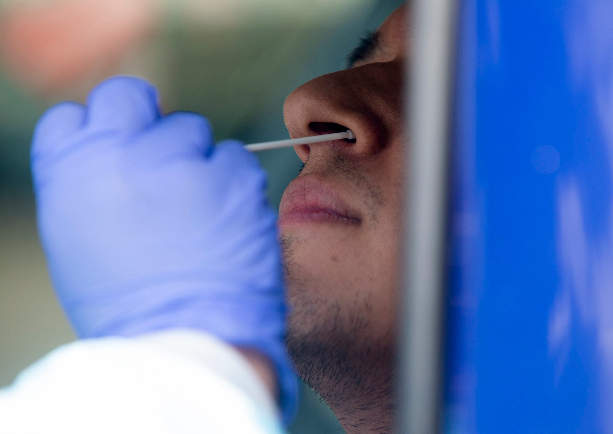 Javier Treviño, a licensed vocational nurse, tests a man for COVID-19 at Austin Regional Clinic Far West's drive-through testing on May 27, 2020. The drive-through saw more than 40 people that day.