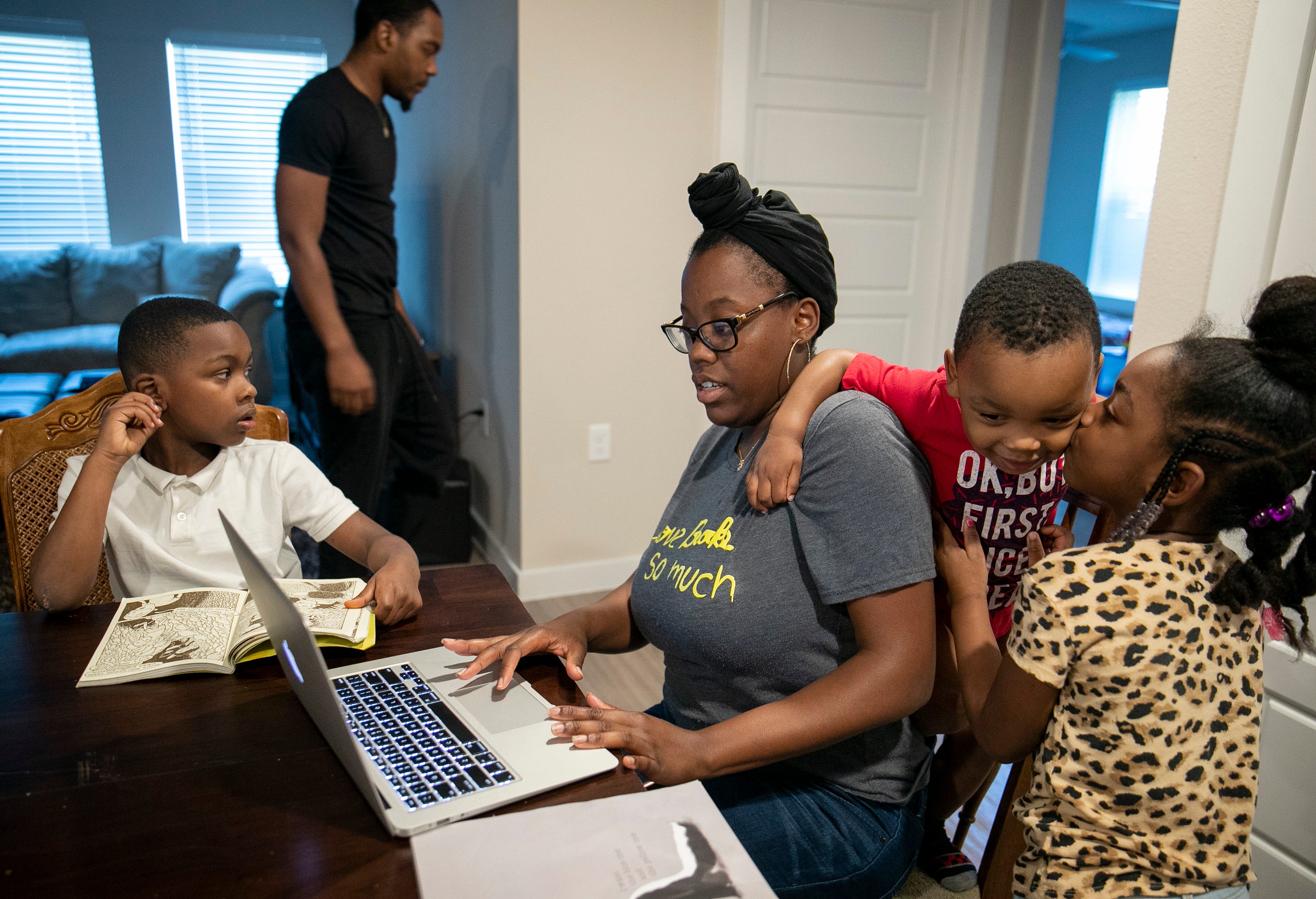 Amber Fowler, a teacher at Brooke Elementary School, tries to login to her school portal to do some work, while sharing space with her husband Jacolby Scott, and their children, Javon Scott, 7, from left, Jacolby Scott Jr., 2, and Jamiyah Scott, 5, at their apartment in South Austin on Wednesday March 25, 2020.  The family is stuck at home while schools are shut down due to the coronavirus pandemic.