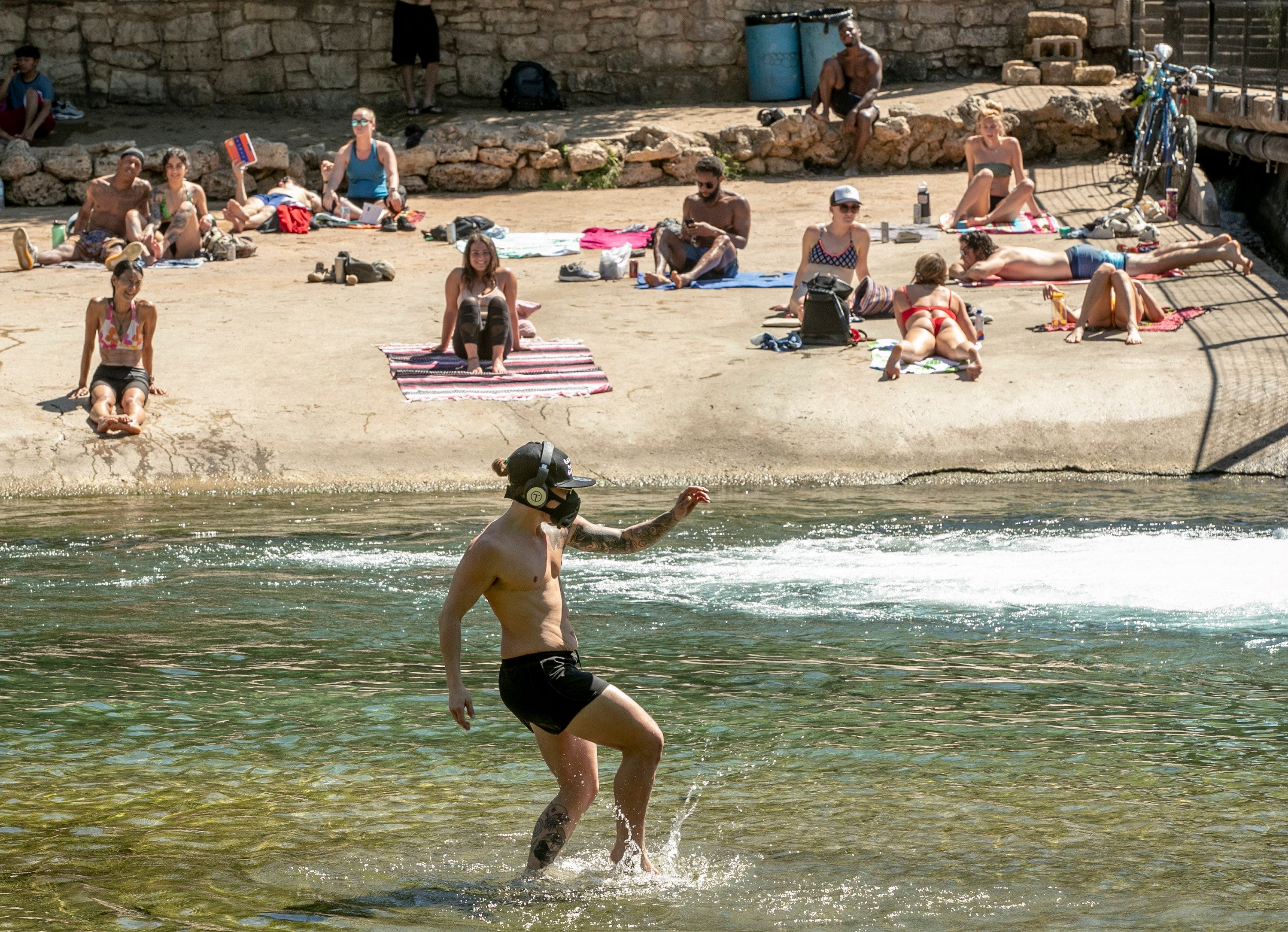 Kristopher McCoy frolics in the cool waters of Barton Creek on March 25, 2020. The Austin area now faces the possibility of returning to its strictest levels of COVID-19 guidelines.