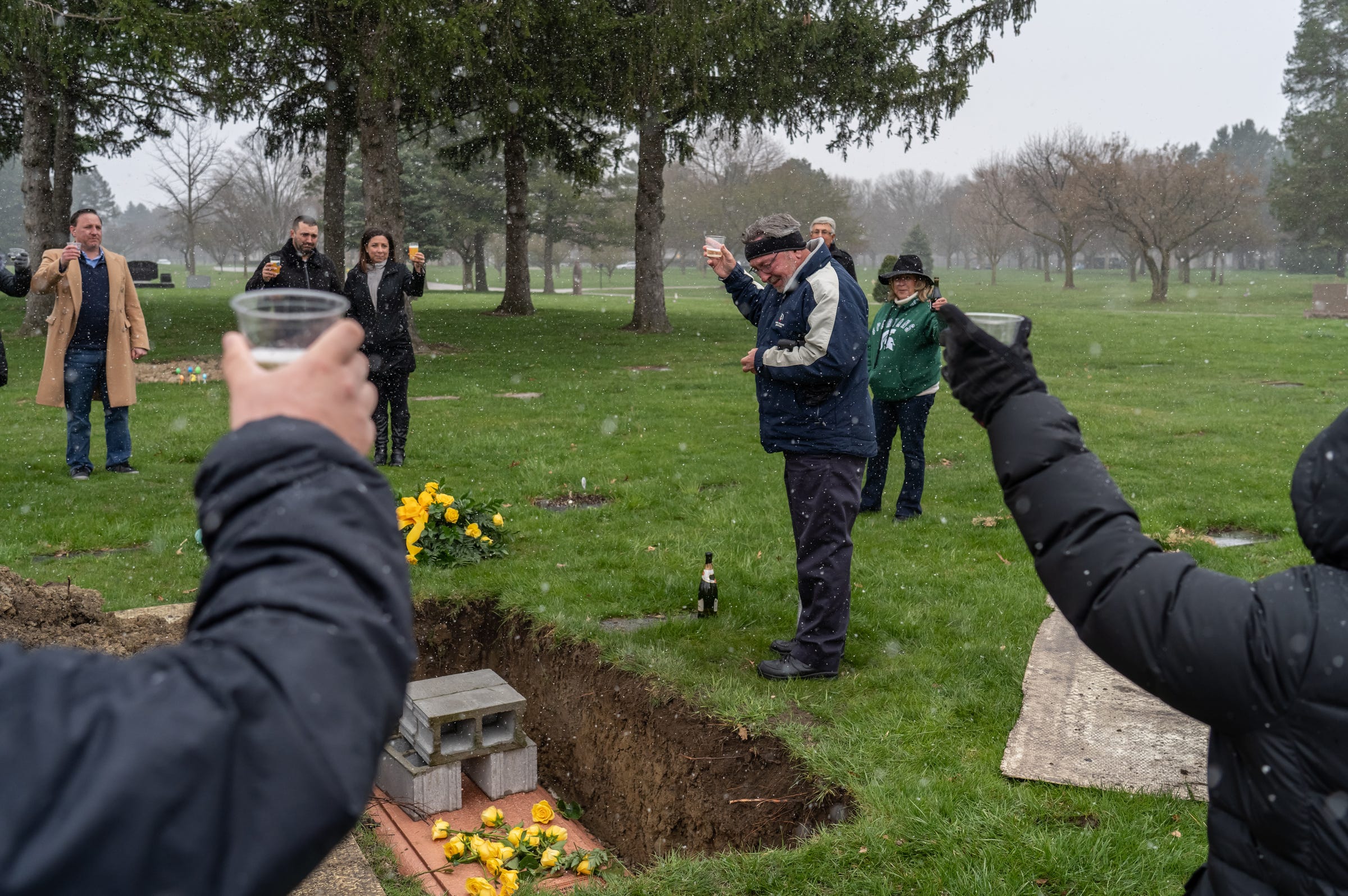 Rocky Richards (center) of Algonac gets emotional while raising a glass in toast to his mother Janice "Granny" Severini, 90, of Shelby Township as the family gathers around her grave on Friday, April 17, 2020 at Resurrection Cemetery in Clinton Township. Richards mother passed away from COVID-19 and the family wasn't able to have a funeral leaving the family saying their last goodbye after her casket was lowered into the ground. "When things change we will have a celebration," Richards said.