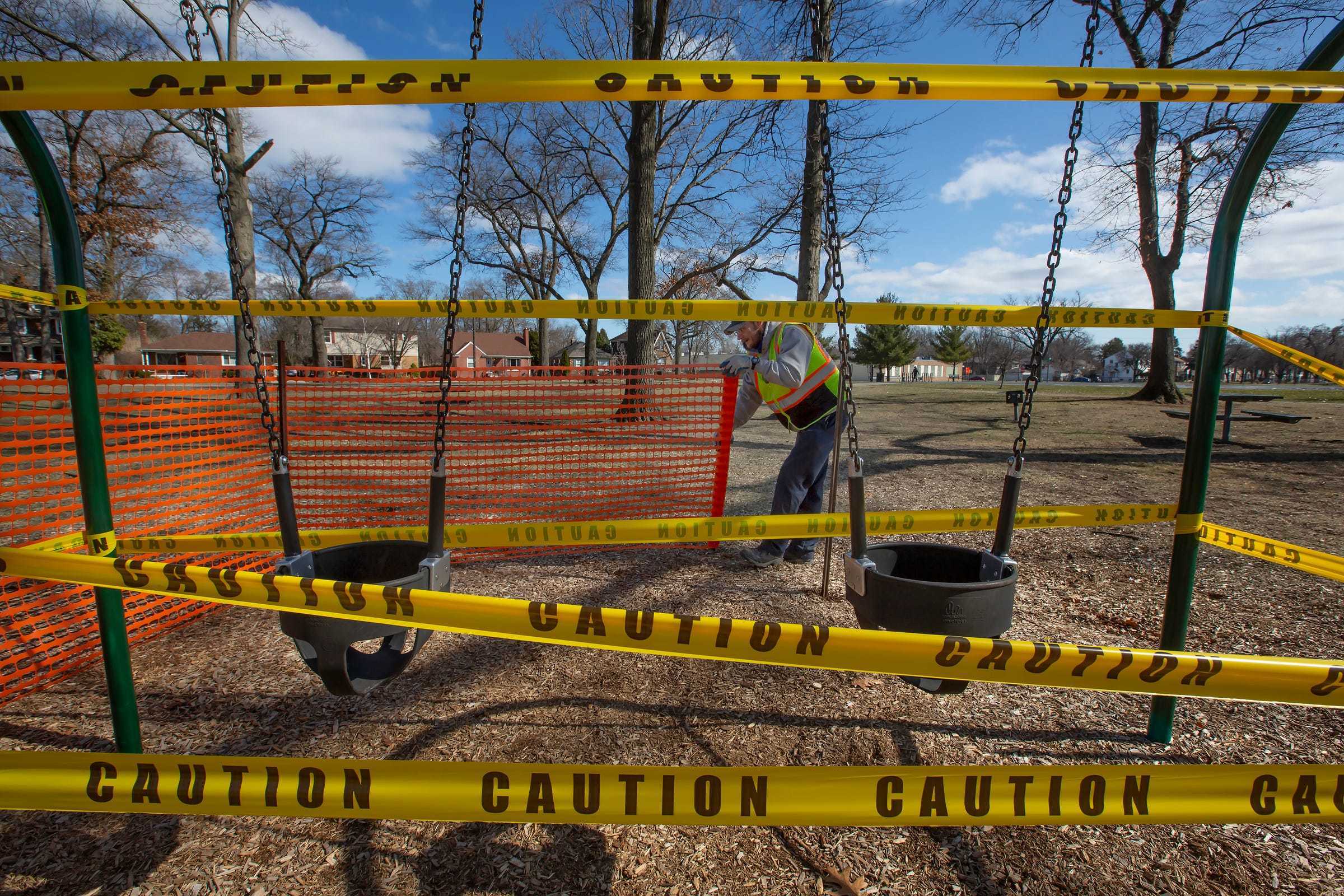 City of Ferndale employee Caleb Clemons, 38, of Ferndale, Michigan erects barriers around a swing set at Garbutt Park on Saturday, March 21, 2020 after Oakland County restricted access to playground equipment and closed shopping malls to try and stop the spread of coronavirus.