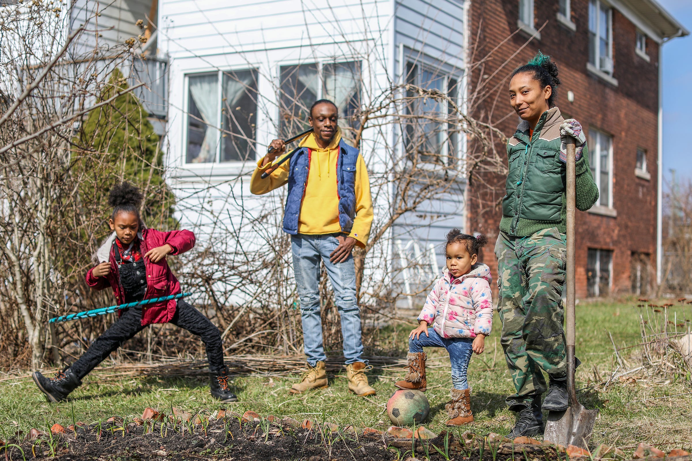 Halima Cassells of Detroit, right, gardens in her backyard with her family: Mia-Rah, 8, Bryce Detroit, and Nzinga, 2. The Cassells and Bryce are community-engaged artists and Bryce said, "It's interesting to do work that serves humanity and at the same time being asked to distance ourselves from humanity." Cassells said coronavirus is causing people to step up their humanity by making the government do the right thing: turning peoples' water back on so that residents can follow CDC guidelines to stay safe.