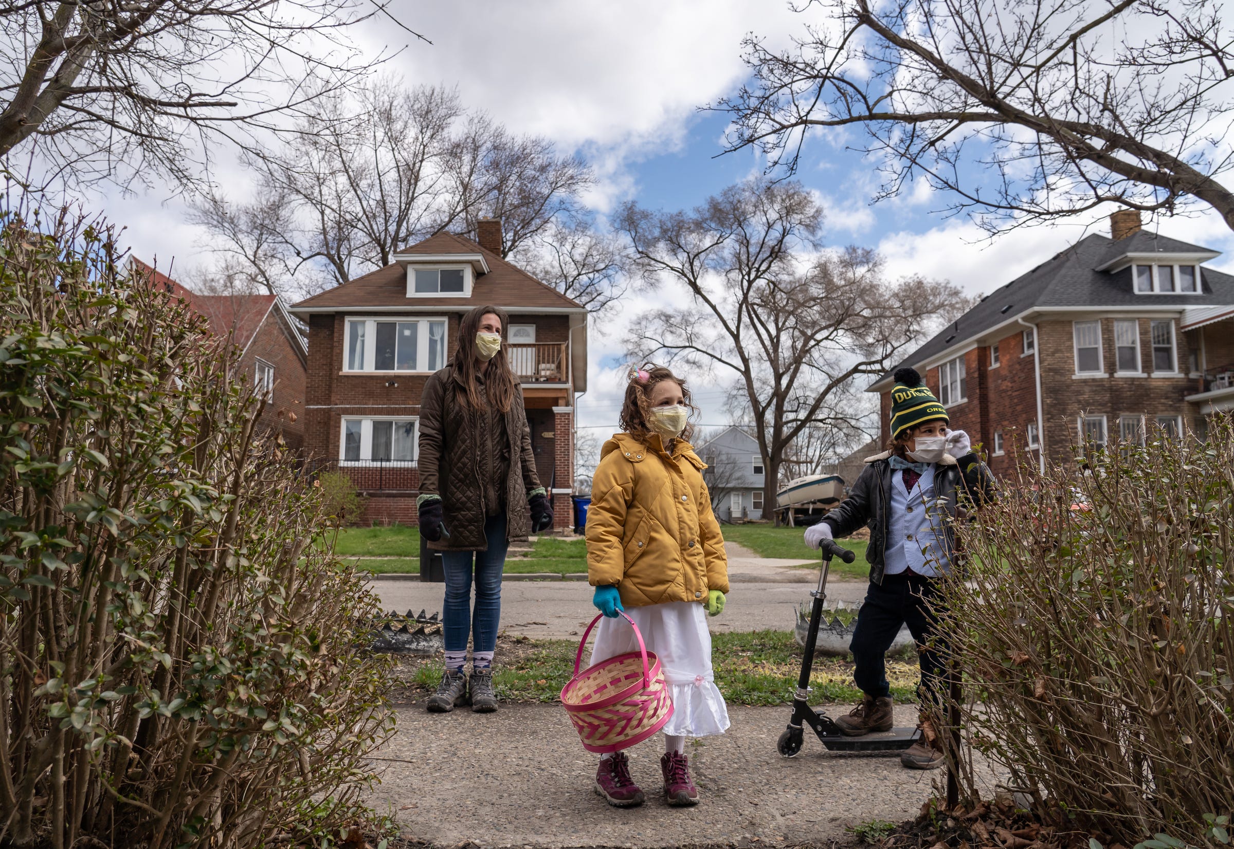 (Left to right) Kaytea Moreno Elst and her children Nilah Moreno Elst and Oskar Tyce Moreno Elst look for Easter eggs while out on a hunt through Pingree Park in Detroit's east side on Friday, April 10, 2020. Neighbors from about 40 houses made giant eggs of paper and hung them in windows of their houses for children of the neighborhood to walk the sidewalk or ride a bike and see if they can hunt for the houses with an egg while keeping tally. 