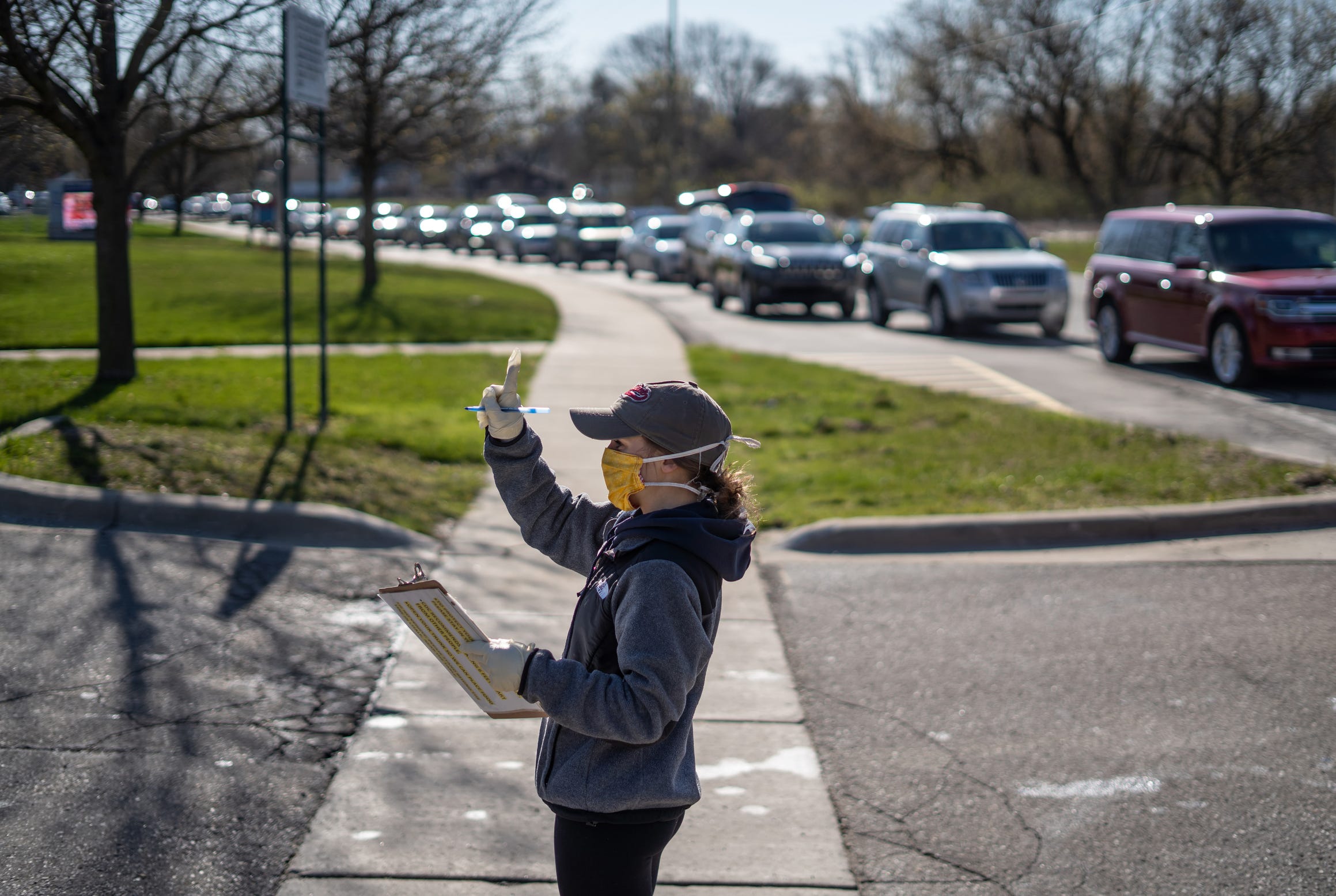 Gleaners Community Food Bank coordinator Chelsea Manning signals the amount of families a person is picking up food for during a food distribution by Gleaners Community Food Bank at the Jefferson Barns Community Vitality Center in Westland on Monday, April 20, 2020.