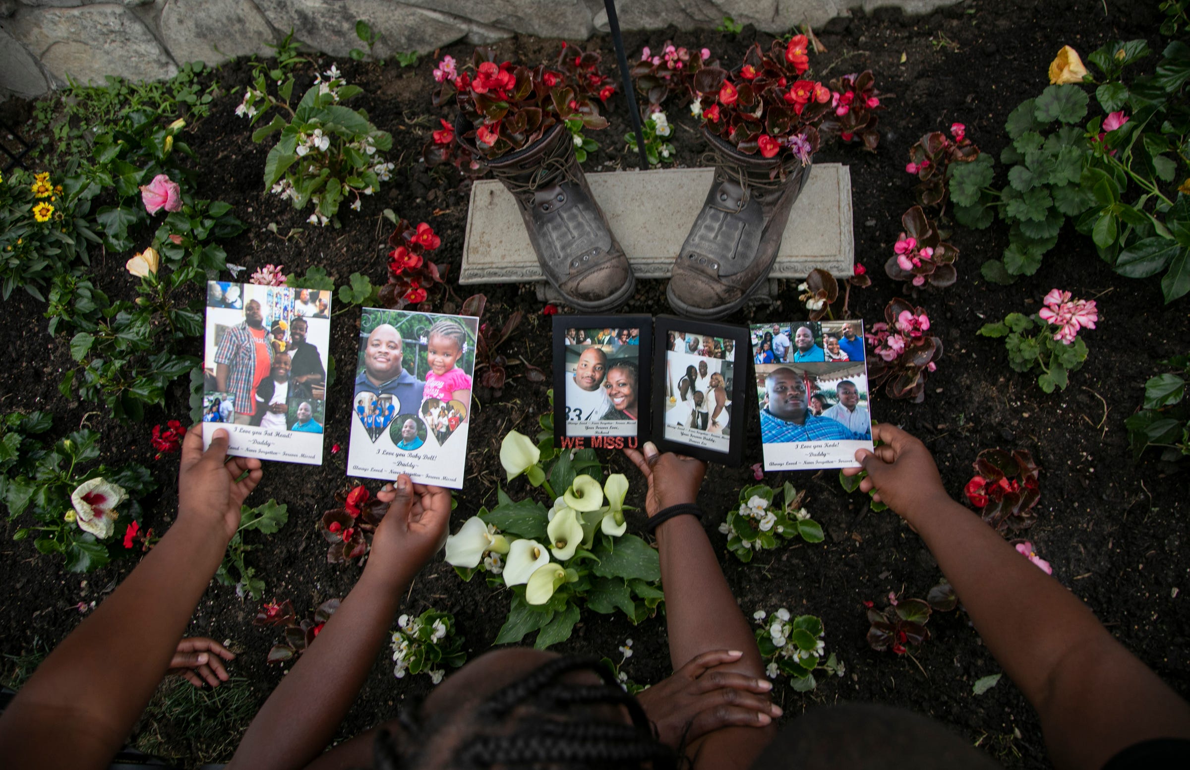 Denise Chandler, 37, of Detroit lost her husband, Richard Chandler, when he died March 29 at Sinai-Grace Hospital in Detroit. Denise Chandler holds personalized photos of her late husband with three of her eight children over the memorial garden that includes her husband's work boots Wednesday, June 24, 2020.