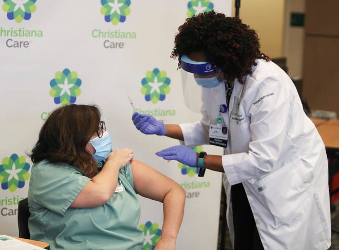 ChristianaCare respiratory therapist Kathleen Bonis receives the COVID-19 vaccine from Christiana Hospital colleague Tabe Mase as the health network starts vaccinating its approximately 13,500 employees Friday, Dec. 18, 2020.
