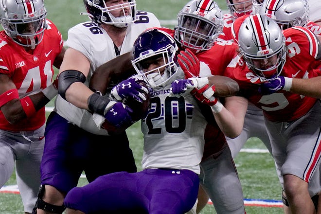 Northwestern running back Cam Porter (20) struggles for yardage during the first half of the Big Ten championship NCAA college football game against Ohio State, Saturday,  in Indianapolis.
