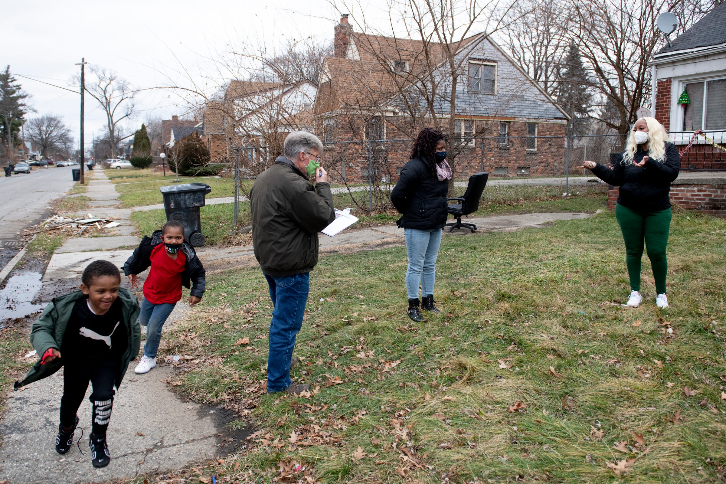 Detroit Eviction Defense volunteers Jim Dwight, and Soummer Crawford, center, discuss available resources with Detroit renter Nia Fitzpatrick during a follow-up visit at Fitzpatrick's home on Sunday, Dec. 13, 2020. Meanwhile Fitzpatrick's sons Anthony, 5, and Clifton, 4, chase each other around the yard. The grass-roots organization helps renters who are at risk for eviction or have other problems with housing.