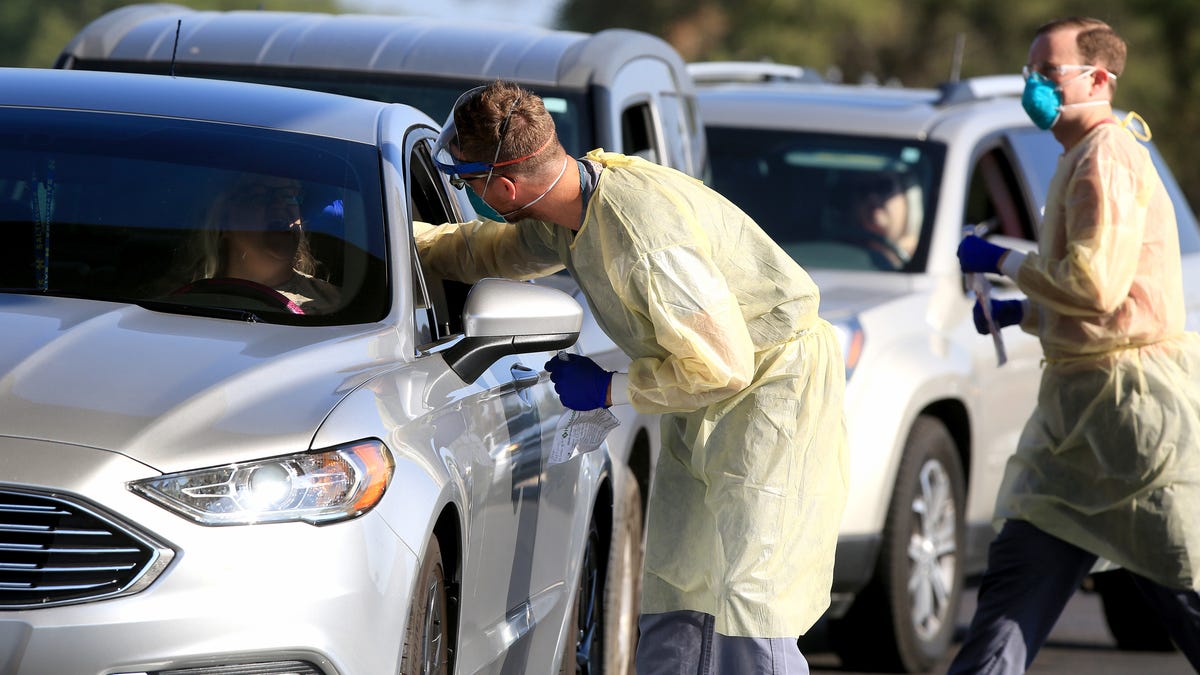 Scott Pauly,a family practitioner at the Hutchinson Clinic, takes a throat swab sample from an educator, as Casey Gee takes a completed sample back to the table during a drive through COVID-19 testing event at the clinic.
