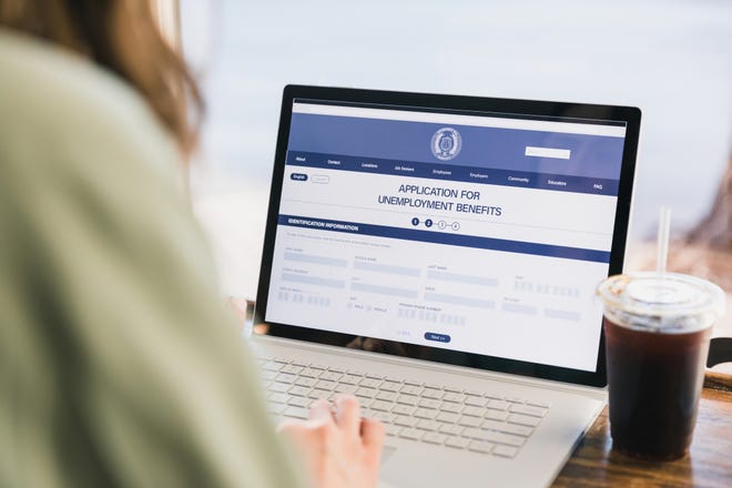 An over the shoulder photo of an unrecognizable woman applying for unemployment benefits.  She is using the government website.