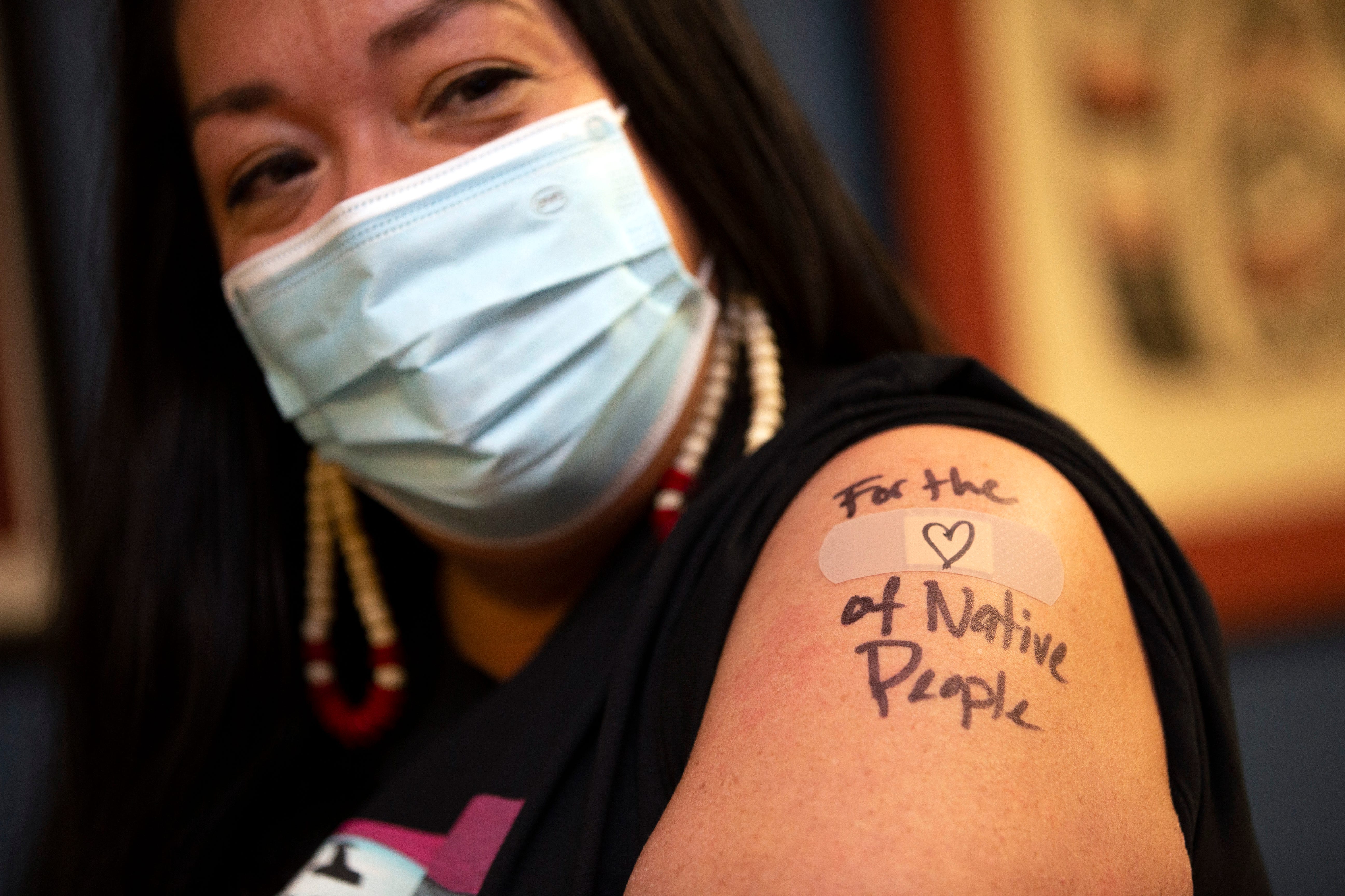 Abigail Echo-Hawk, chief research officer with the Seattle Indian Health Board and a member of the Pawnee Tribe, shows off her arm after she received a shot of the Moderna COVID-19 vaccine in Seattle. A colleague used a black pen to inscribe "For the (Heart) love of Native People" over the spot where she got the injection.
