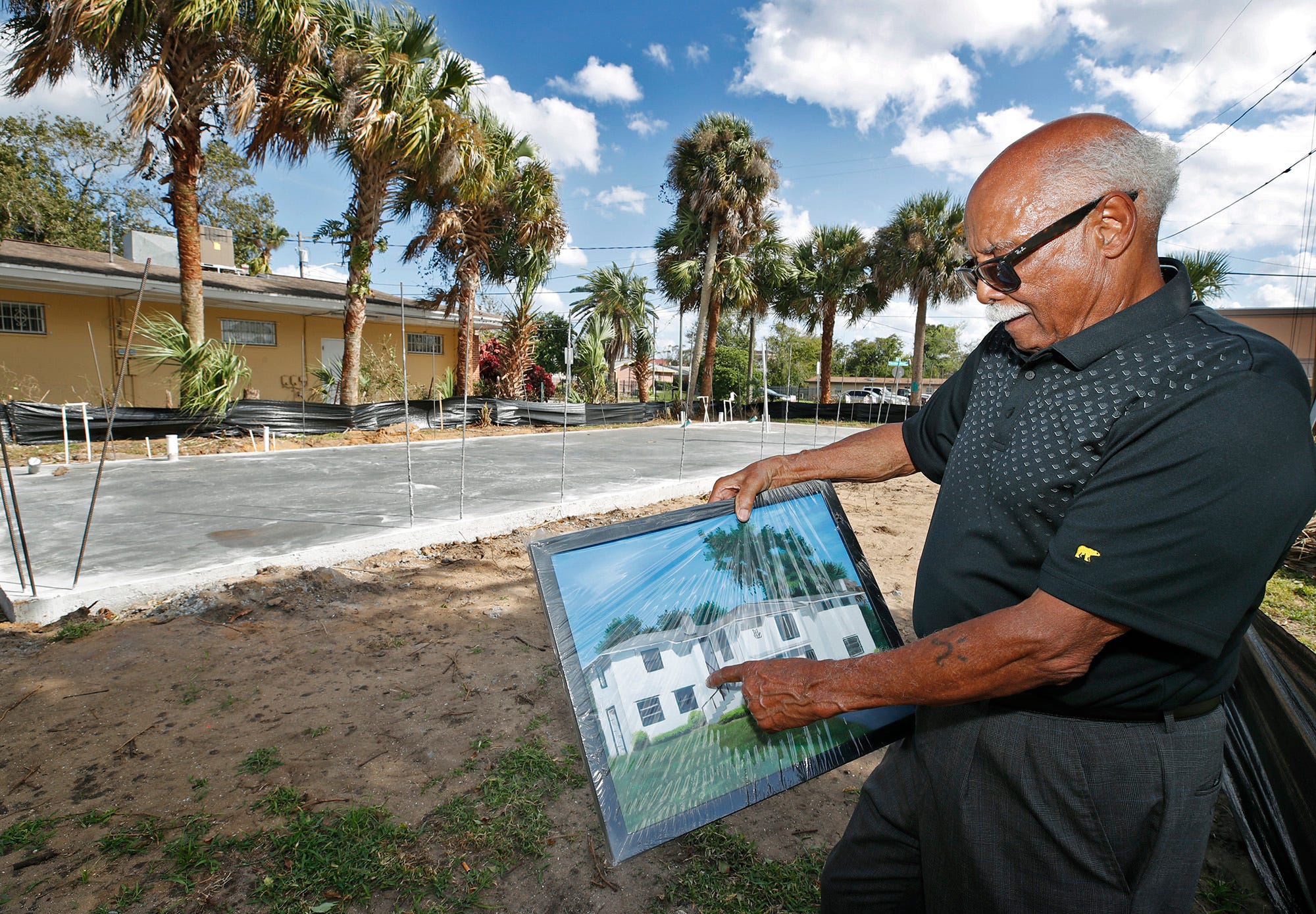 Harold V. Lucas Jr. shows a picture of the home he was born and raised in. He's shown standing on the site of the home located at the corner of Mary McLeod Bethune Boulevard and Jefferson Street. He had the home demolished after someone drove their car into it. He's now building a structure that will house his personal mementos and his memorabilia of Mary McLeod Bethune, and provide space for meetings.