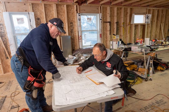 Dave Rushing, left, and Tom Wencel look over blueprints as they work on an addition of a second level to Wencel's home on Tulane Street in Dearborn Heights,  Dec. 24, 2020.  Dozens of volunteers are helping Wencel and his wife, Debbie, with the expansion which will add room for the couple's five young grandchildren, whom they've fostered since their 36-year-old daughter, Jaime Wencel, died of a heart attack on July 11, 2017.
