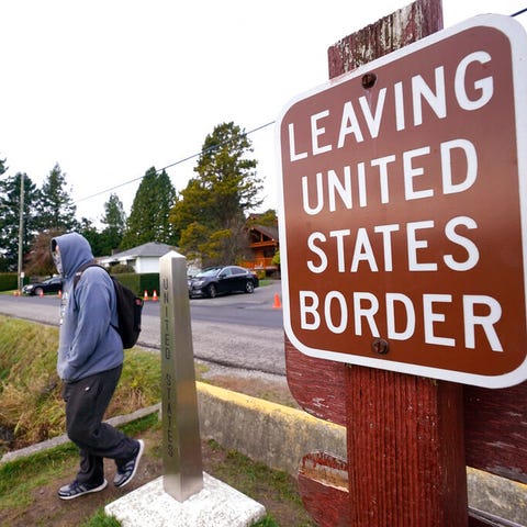 A Canadian citizen steps past a border marker and 