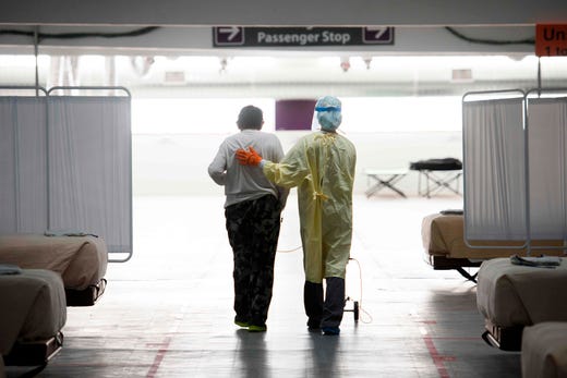 A nurse supports a patient as they walk in the COVID-19 alternative care site, built into a parking garage, at Renown Regional Medical Center, Dec. 16, 2020 in Reno, Nev. Renown Health converted two floors of a parking garage into an alternative care site for Covid-19 patients to increase hospital capacity amid a surge in cases, allowing other facilities to be used for patients in more serious condition.