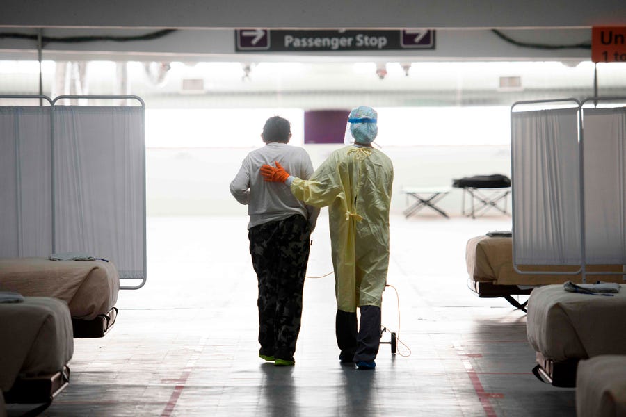 A nurse supports a patient as they walk in the COVID-19 alternative care site, built into a parking garage, at Renown Regional Medical Center, Dec. 16, 2020 in Reno, Nev.  Renown Health converted two floors of a parking garage into an alternative care site for Covid-19 patients to increase hospital capacity amid a surge in cases, allowing other facilities to be used for patients in more serious condition.
