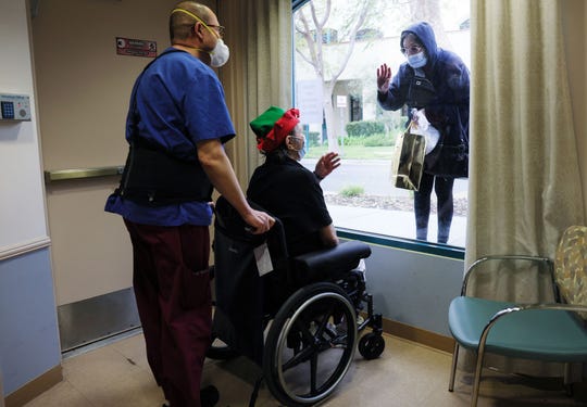 Juliet Babayan holds a gift for her sister Violet Bonyad as they visit through a window at the Ararat Nursing Facility on Christmas Eve on December 24, 2020 in Mission Hills, California.