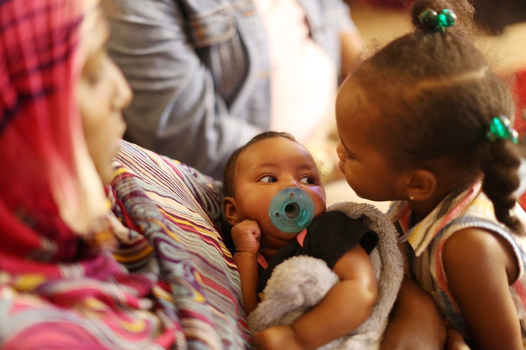 Zahra Younous, holds her two month old daughter, Sujud Adam, while her other daughter, Sadan Adam, 2, gives her new sister a kiss. Thursday, August 16, 2018. Younous participates in a program to help reduce infant mortality.   (Dispatch photo by Courtney Hergesheimer)