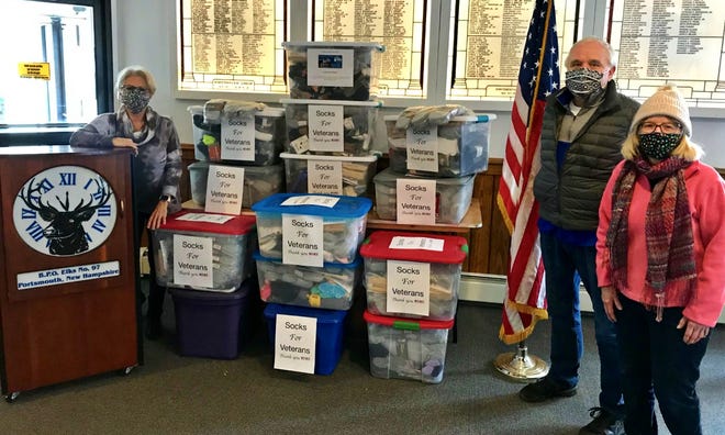 Portsmouth Elks members, from left, Marga Coulp, Michael Griffin and Sue Talhouk, are seen Wednesday, Dec. 30, 2020 with more than 2,000 pairs of socks the lodge collected this holiday season for veterans across New Hampshire.