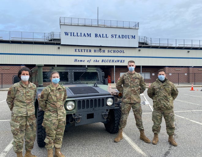 New Hampshire National Guard members, from left, Maj. Tori Scearbo, Staff Sgt. Megan Turgeon, Specialist Zachary Phillips and Specialist Zachary Bolduc are seen in the Exeter High School football stadium parking lot, where the National Guard is staging a COVID-19 vaccination site for first responders.