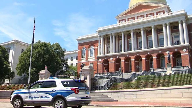A Boston police cruiser is parked outside the State House. Gov. Charlie Baker on Thursday signed into law a police reform bill.