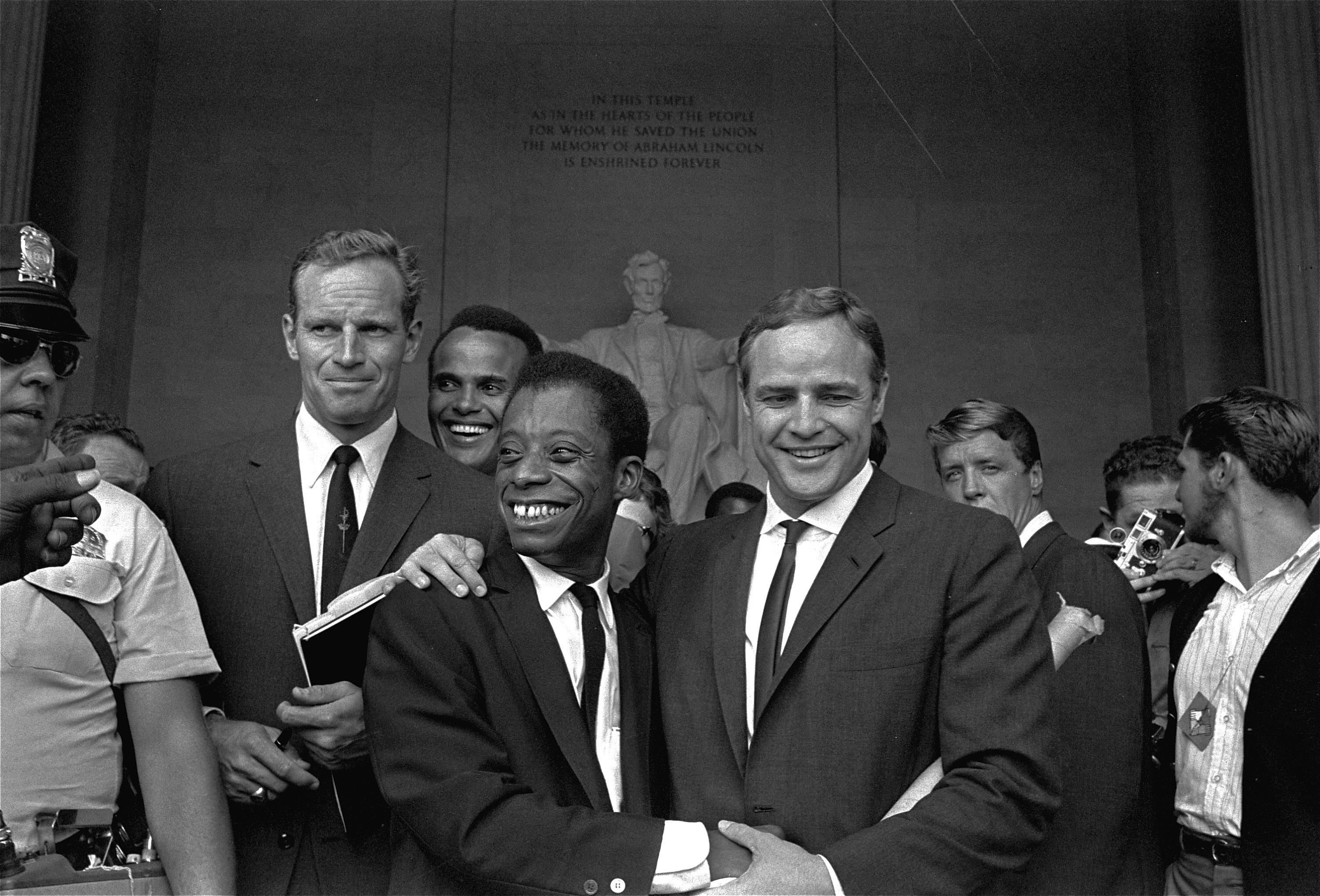 Actor Marlon Brando, right, poses with his arm around James Baldwin, author and civil rights leader, in front of the Lincoln statue at the Lincoln Memorial, August 28, 1963, during the March on Washington demonstration ceremonies which followed the mass parade.  Posing with them are actors Charlton Heston, left, and Harry Belafonte.  (AP Photo) ORG XMIT: APHS200 [Via MerlinFTP Drop]